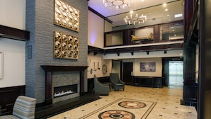 A lobby with a fireplace, seating area, and a decorative floor pattern.