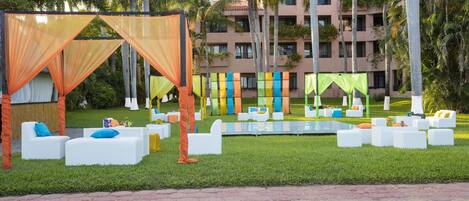 A poolside area with white lounge chairs and a canopy.