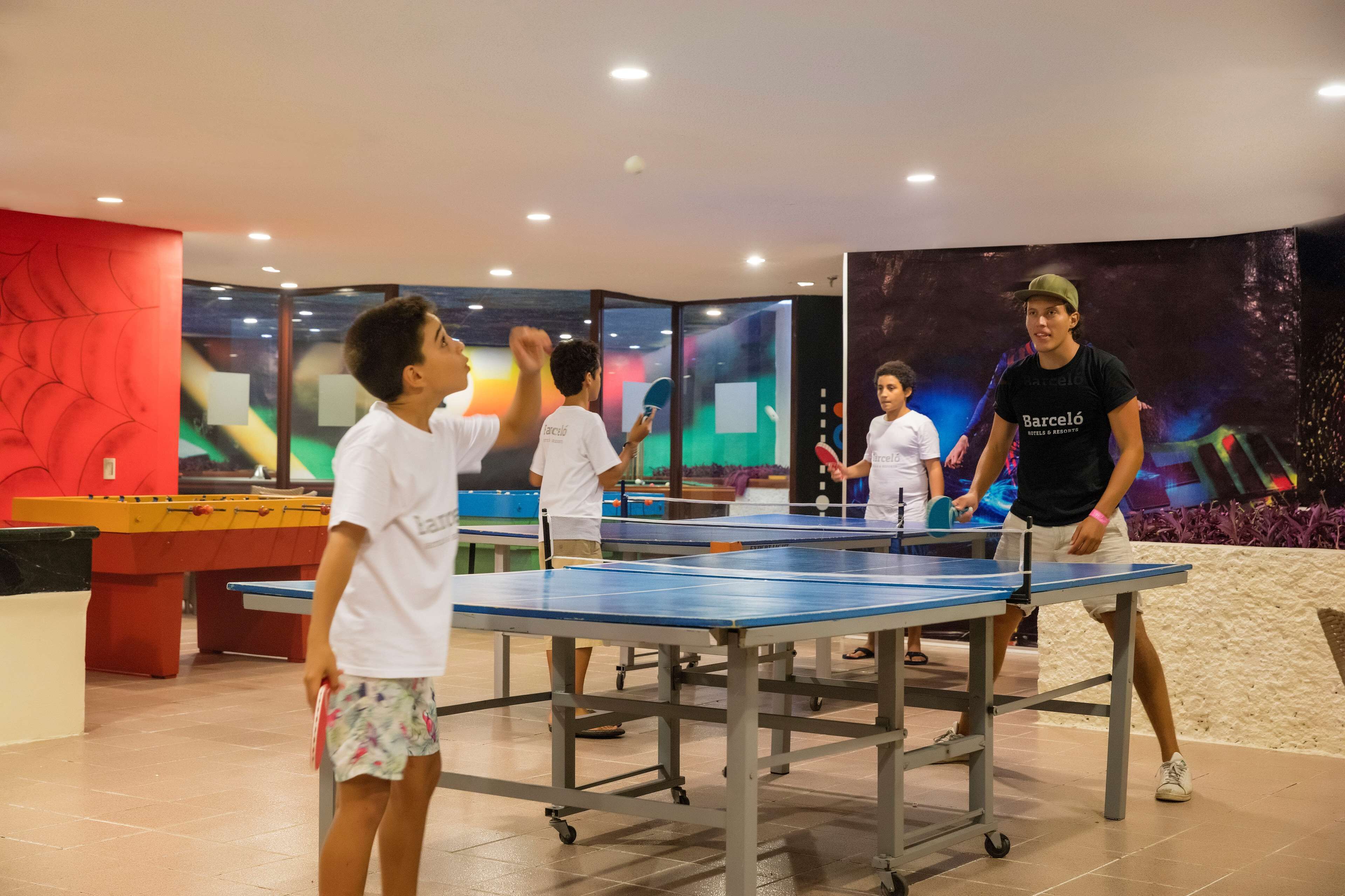 Une table de ping-pong dans un espace intérieur bien éclairé, avec un mur rouge et un grand écran affichant des graphiques colorés.