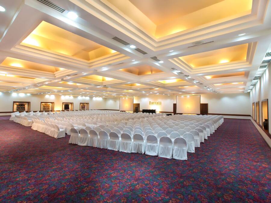 A large hall with rows of white chairs and a carpeted floor.