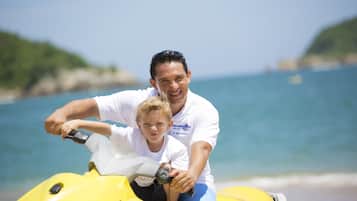 A man and a child on a yellow jet ski at the beach.