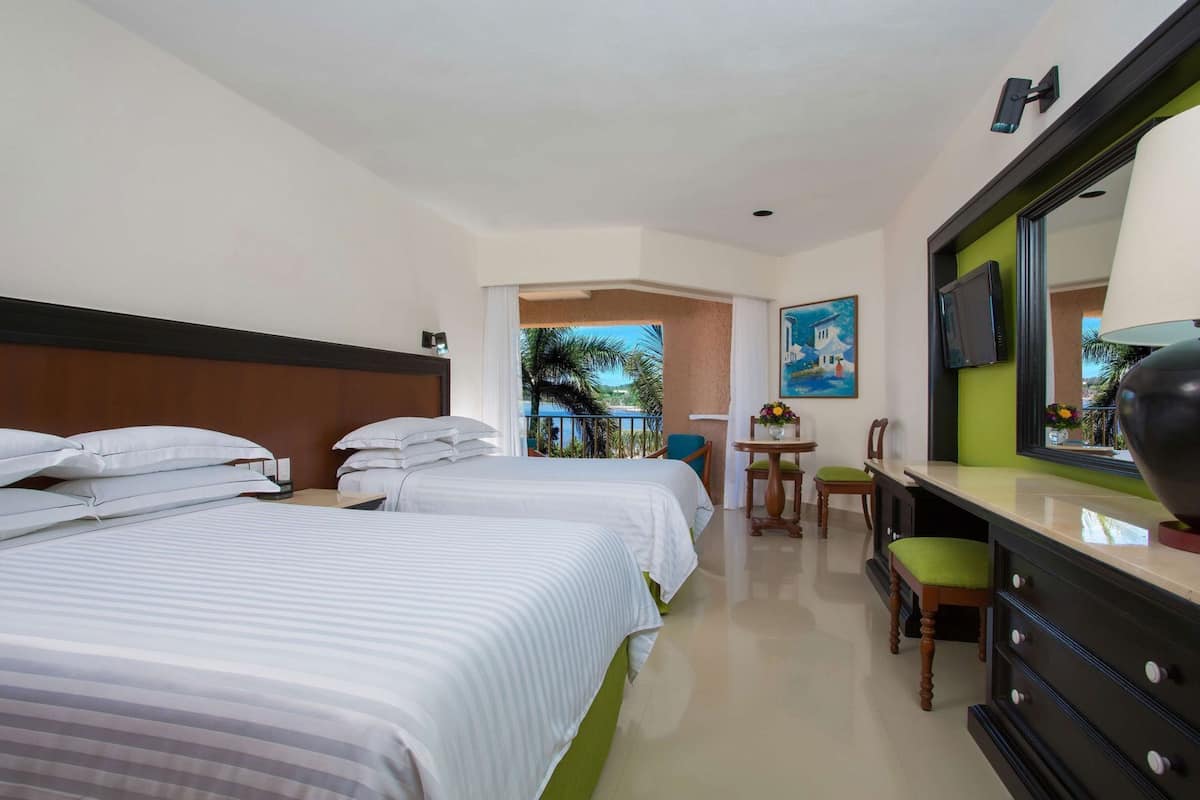 A hotel room with two beds, a desk with a chair, a television, and a painting on the wall.