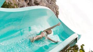 A person in a swimsuit sliding down a clear water slide.