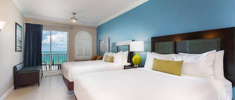 A hotel room with two beds, a balcony with a view, and a ceiling fan.