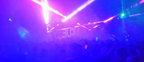 A crowded indoor space with visible stage lighting and a crowd of people.