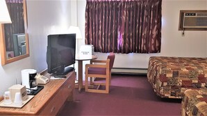 A hotel room with a desk, a television, a chair, a bed, and a window with curtains. - AmeriVu Inn & Suites - Avon (Avon)
