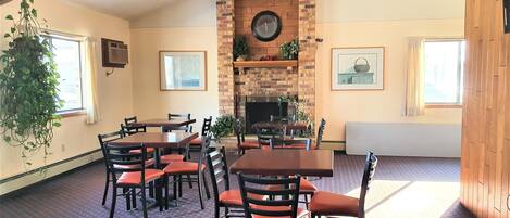 A dining area with brick walls, a fireplace, and a ceiling fan.