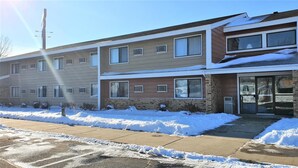 A two-story apartment building with a brick facade and large windows. - AmeriVu Inn & Suites - Avon (Avon)
