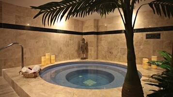 Relax in a serene bathroom with a central hot tub, bathtub, and decorative plant.