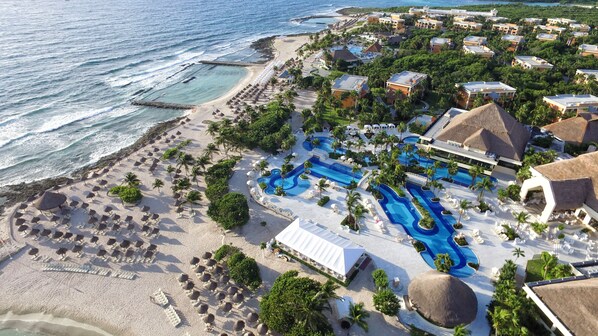 Relax by the infinity pool overlooking the ocean, surrounded by lush greenery and a well-maintained beach.