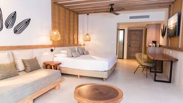 Un dormitorio moderno con una cama, cabecera de madera, mesitas de noche, una mesa de centro redonda de madera y un comedor con mesa y sillas.