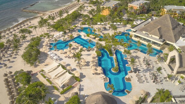 An aerial view of a resort with multiple swimming pools, beach areas, and palm trees. - Bahia Principe Explore Akumal - Hyatt Inclusive Collection - All Inclusive (Akumal)