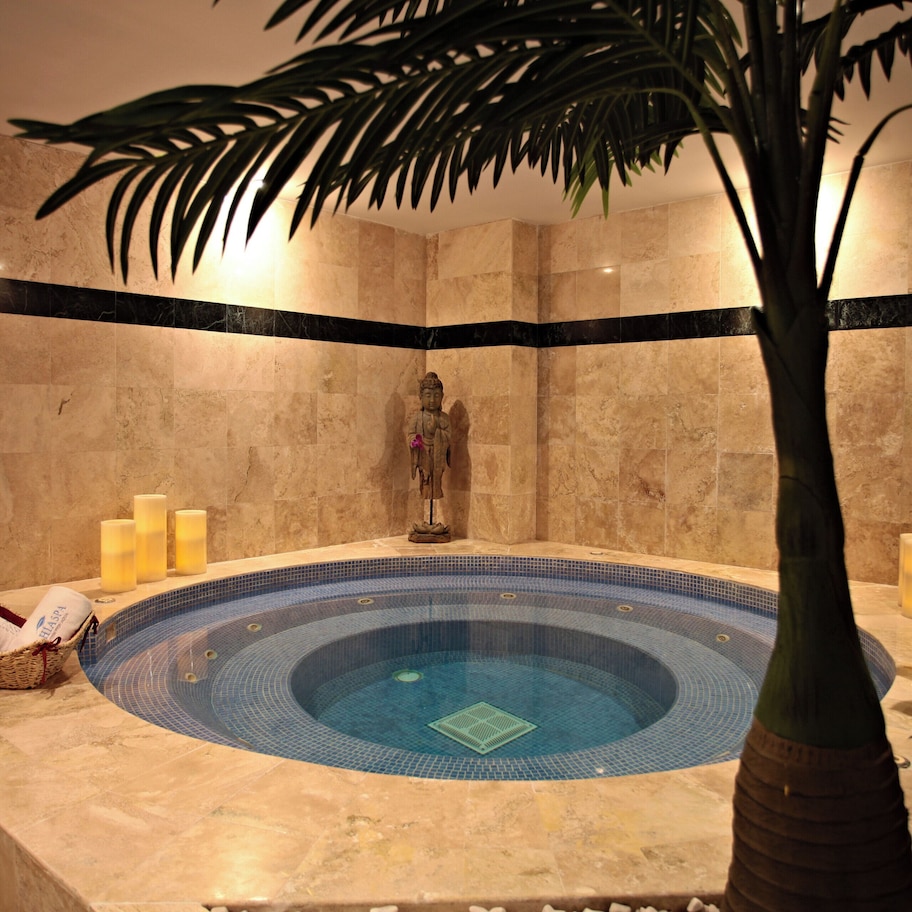 A spa area with a hot tub, candles, and a statue.