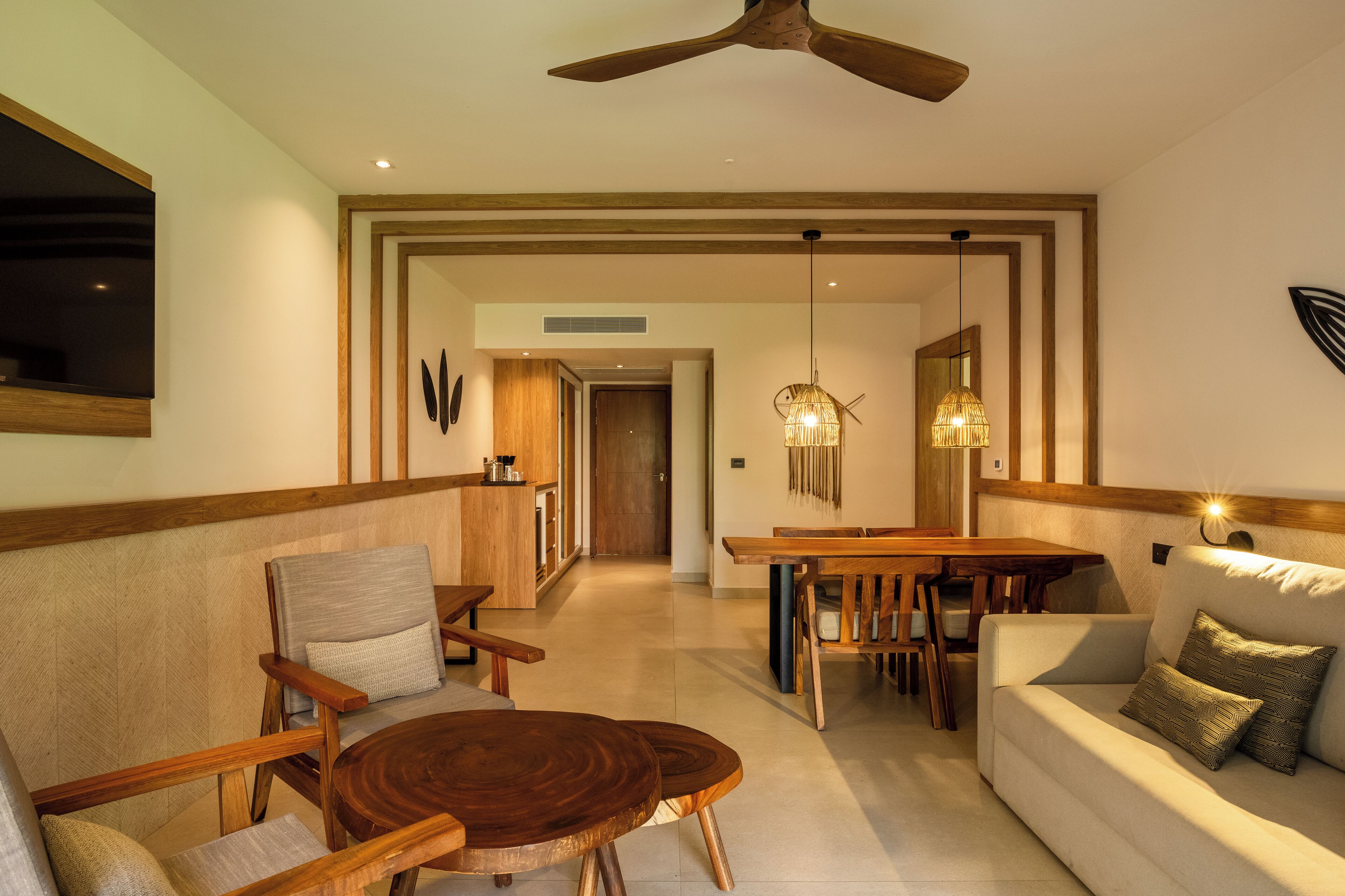 A modern living room with a wooden dining table, a sofa, and a ceiling fan.