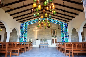 L’intérieur d’une église, avec ses bancs, un crucifix et de magnifiques vitraux aux couleurs vives.