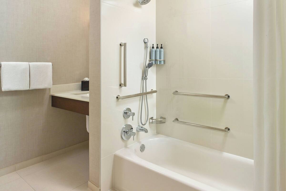Un baño moderno con bañera, ducha y barras de apoyo.