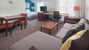 A hotel room with a bed, desk, chair, sofa, and a TV.