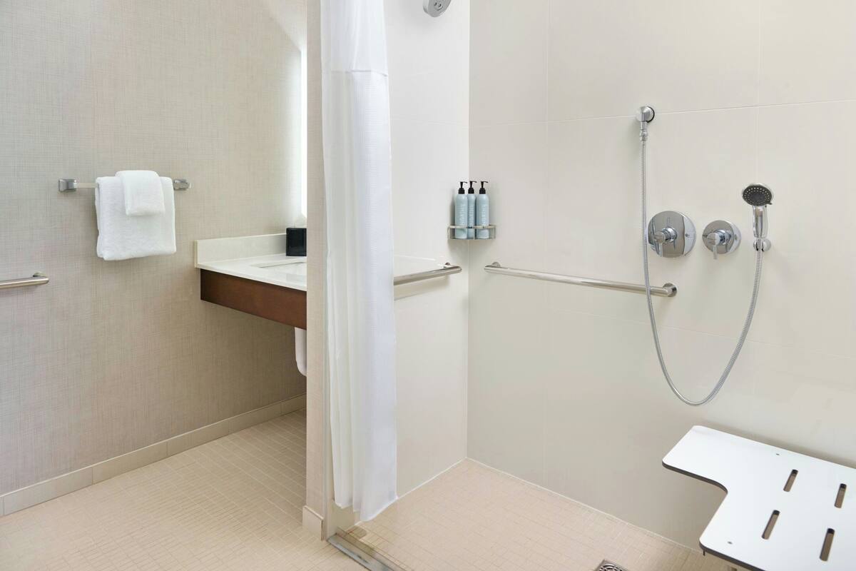 Un baño moderno con ducha, toallero y tocador con espejo.