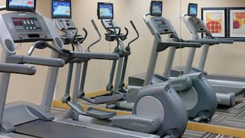 Varias bicicletas estáticas en línea, con pantallas digitales, un panel de control y una cinta de correr.