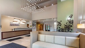 A modern lobby with a reception desk, a sofa, and a hanging light fixture. - Sleep Inn & Suites Lebanon - Nashville Area (Lebanon)