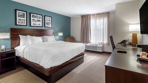 A hotel room with a large bed, a desk, a chair, a TV, and framed pictures on the wall. - Sleep Inn & Suites Lebanon - Nashville Area (Lebanon)
