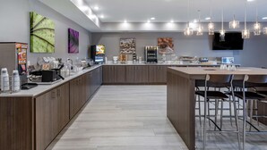 A modern kitchen with a central island, bar stools, and a flat-screen TV mounted on the wall. - Sleep Inn & Suites Lebanon - Nashville Area (Lebanon)