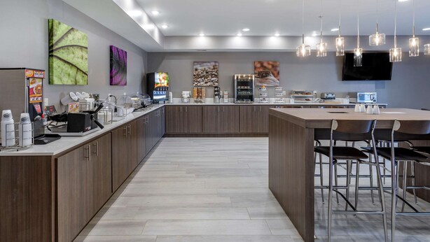 A modern kitchen with a central island, bar stools, and a flat-screen TV mounted on the wall. - Sleep Inn & Suites Lebanon - Nashville Area (Lebanon)