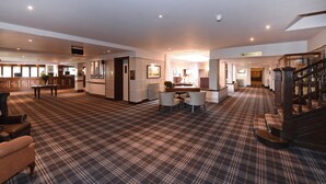 A spacious lobby with a checkered carpet, a reception desk, seating area, and a staircase. - The Old Ship Hotel (Brighton)