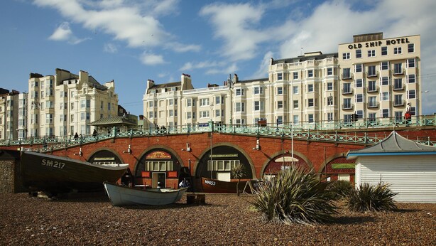 A coastal building with a bridge, a boat, and a small structure. - The Old Ship Hotel (Brighton)