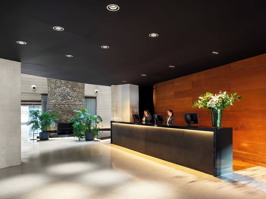 A modern reception area with a dark ceiling, a reception desk, and potted plants.
