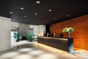 Welcome to our contemporary reception area, featuring a sleek reception desk and a natural stone wall.