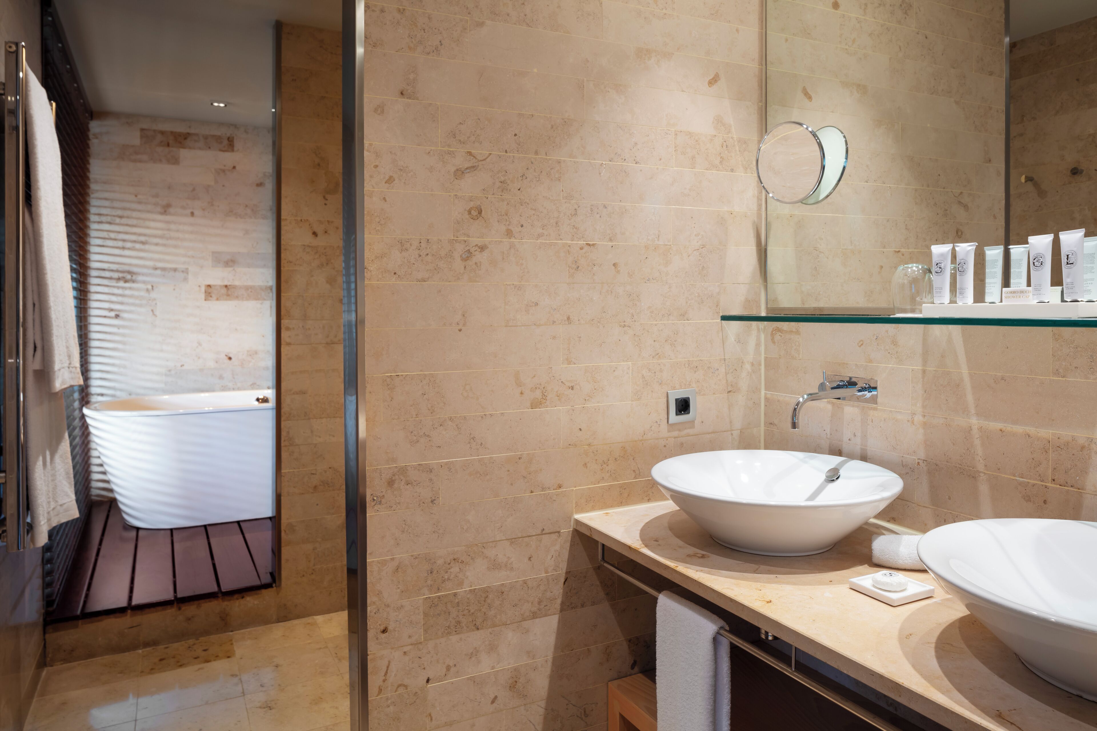 A modern bathroom with two white sinks, a glass shower enclosure, and a large mirror above the sink.