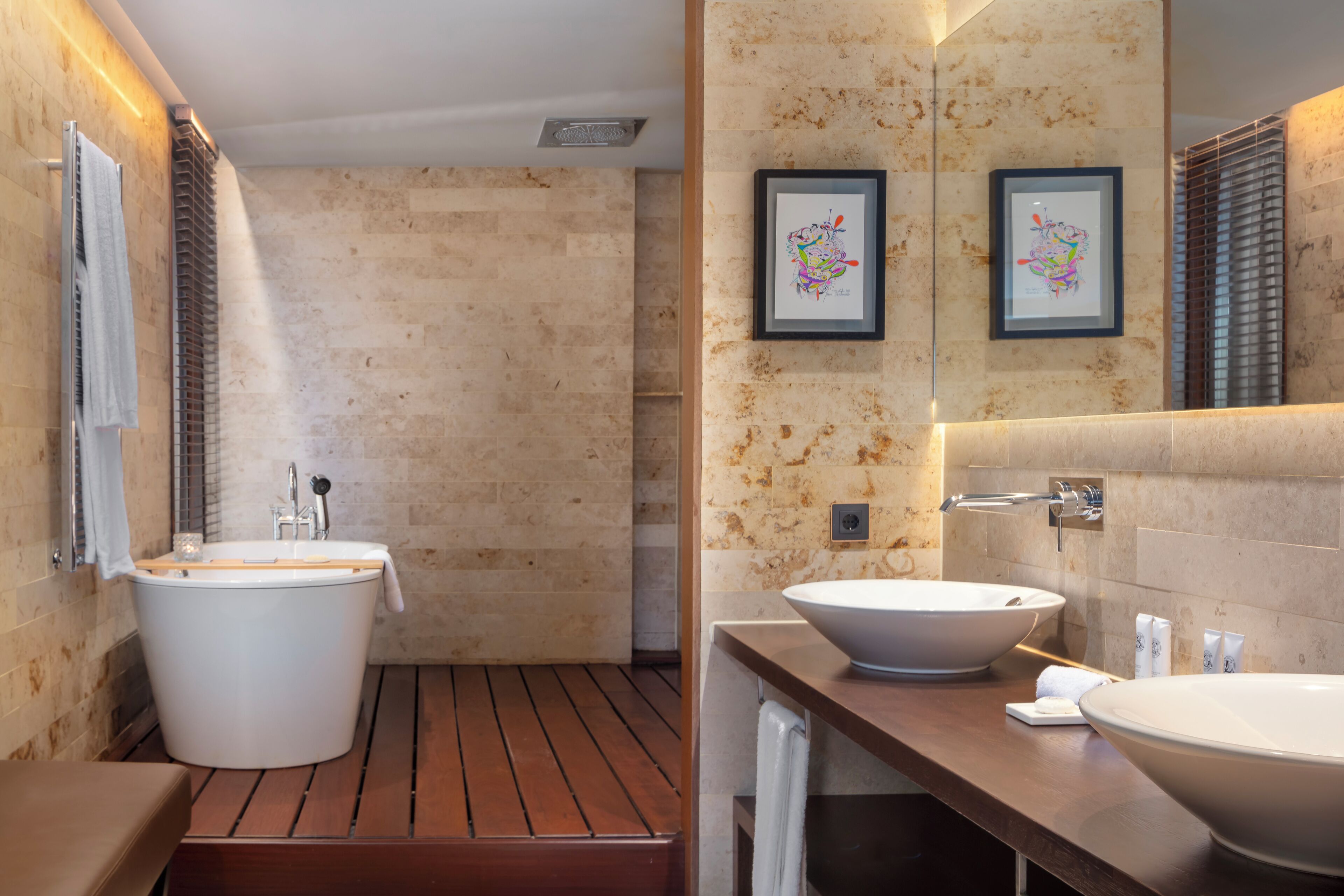 Ein modernes Badezimmer mit einer freistehenden Badewanne, zwei Waschbecken und gerahmten Kunstwerken an der Wand.