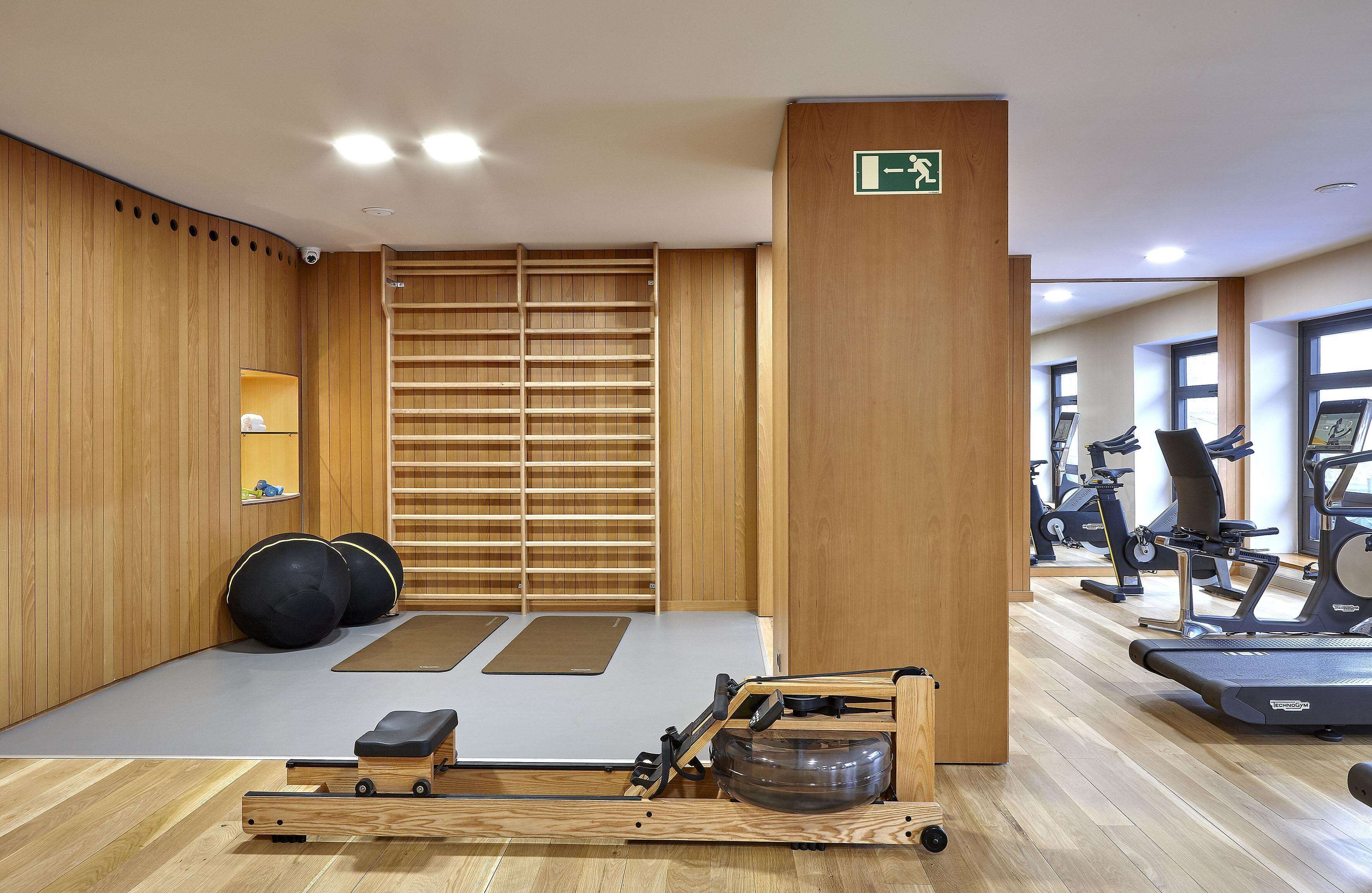 Un gimnasio con paredes de madera, equipamiento para ejercicios y una zona de colchonetas.