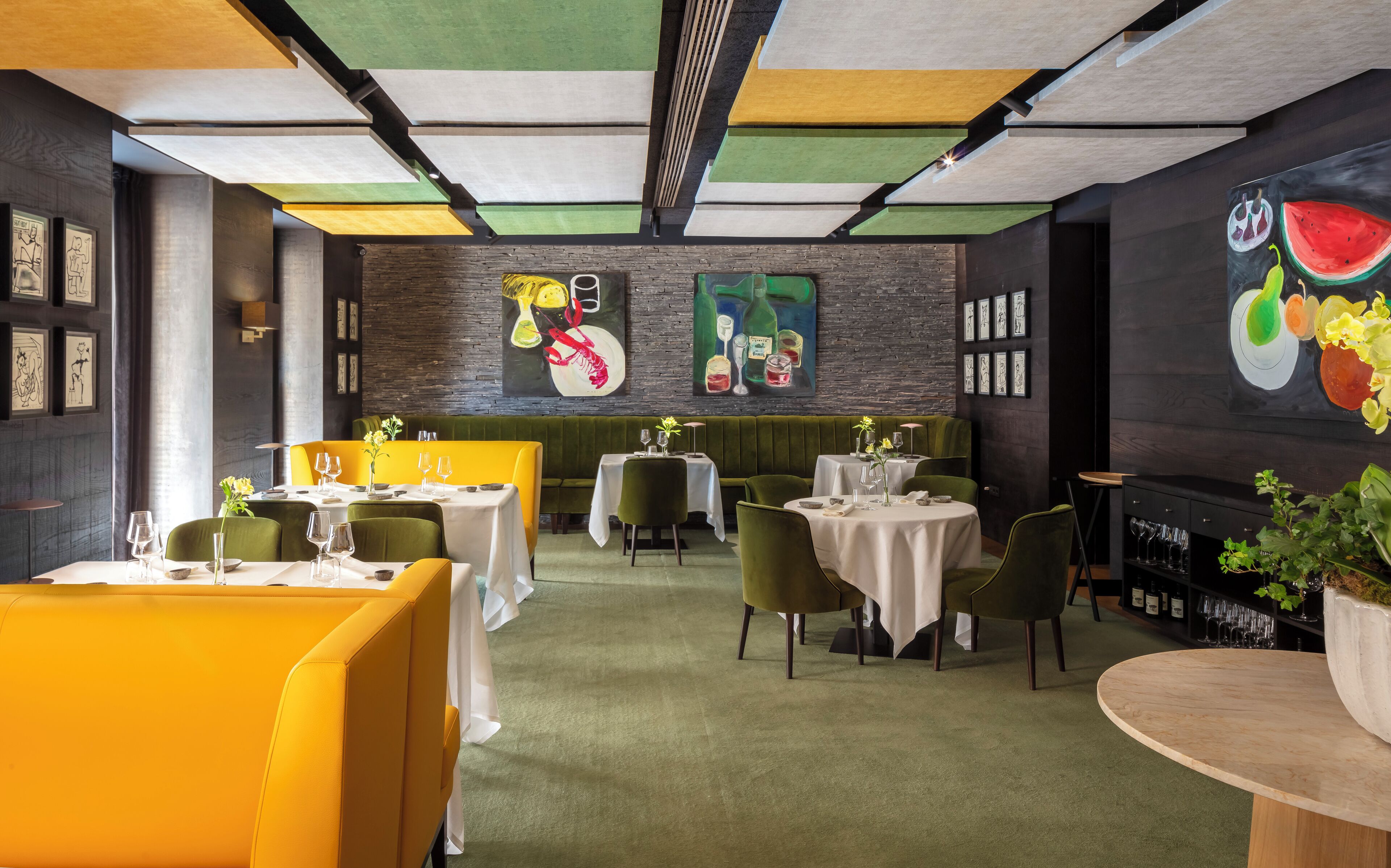 A restaurant with a modern interior, featuring green and yellow seating, white tables, and artwork on the walls.