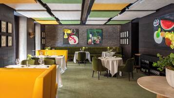 A restaurant with a modern interior, featuring green and yellow seating, white tables, and artwork on the walls.