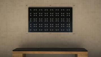 A bench with a dark cushion in front of a wall with a patterned design.