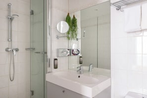 A modern bathroom with a glass-enclosed shower, a white sink, and a large mirror. - Hôtel George - Astotel (Paris)