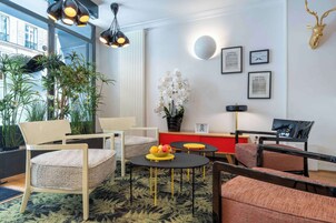 Un salon moderne avec un canapé, des fauteuils, une table basse sur laquelle on a disposé des fruits, un buffet rouge et une décoration représentant une tête de cerf.