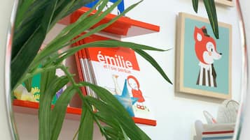 Un espejo redondo con una planta frente a una estantería con libros y fotografías enmarcadas.