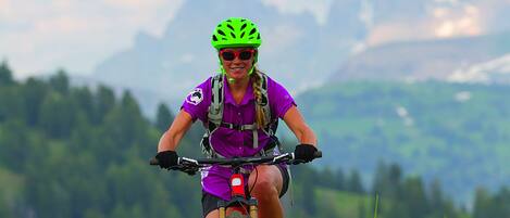 A mountain biker on a trail with a mountainous backdrop.