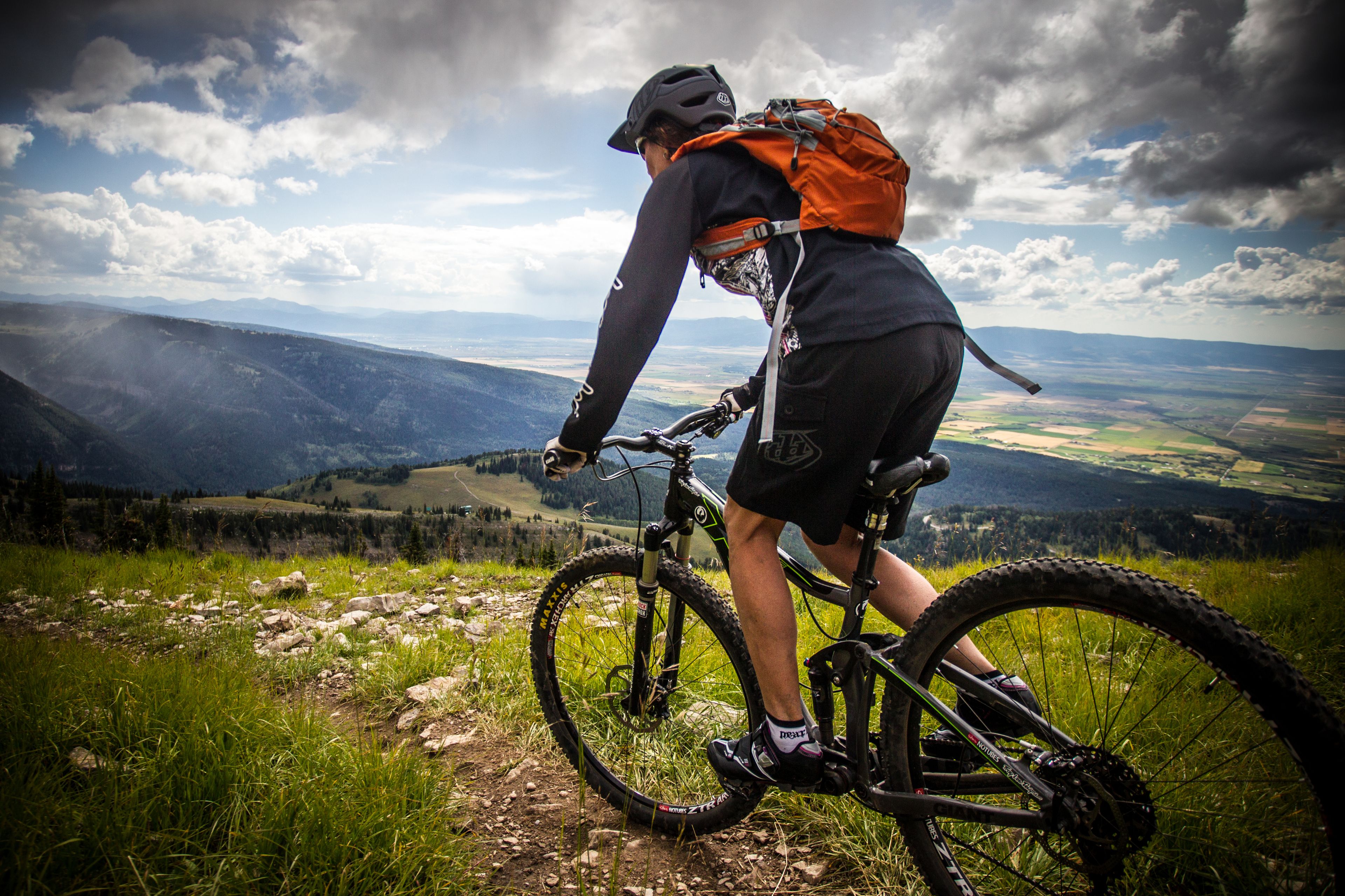 A mountain biker on a trail with a view of distant mountains and valleys.