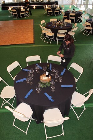Een ronde tafel met stoelen, een fles wijn en glazen, op een groen tapijtvloer.
