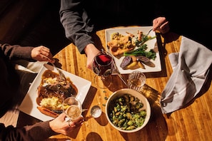 Ein Holztisch mit Speisen, Weingläsern und einer Schüssel mit Gemüse.