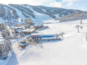 Ein Skigebiet mit einer Liftstation, Skipisten und einem Gebäude mit einem Schild.