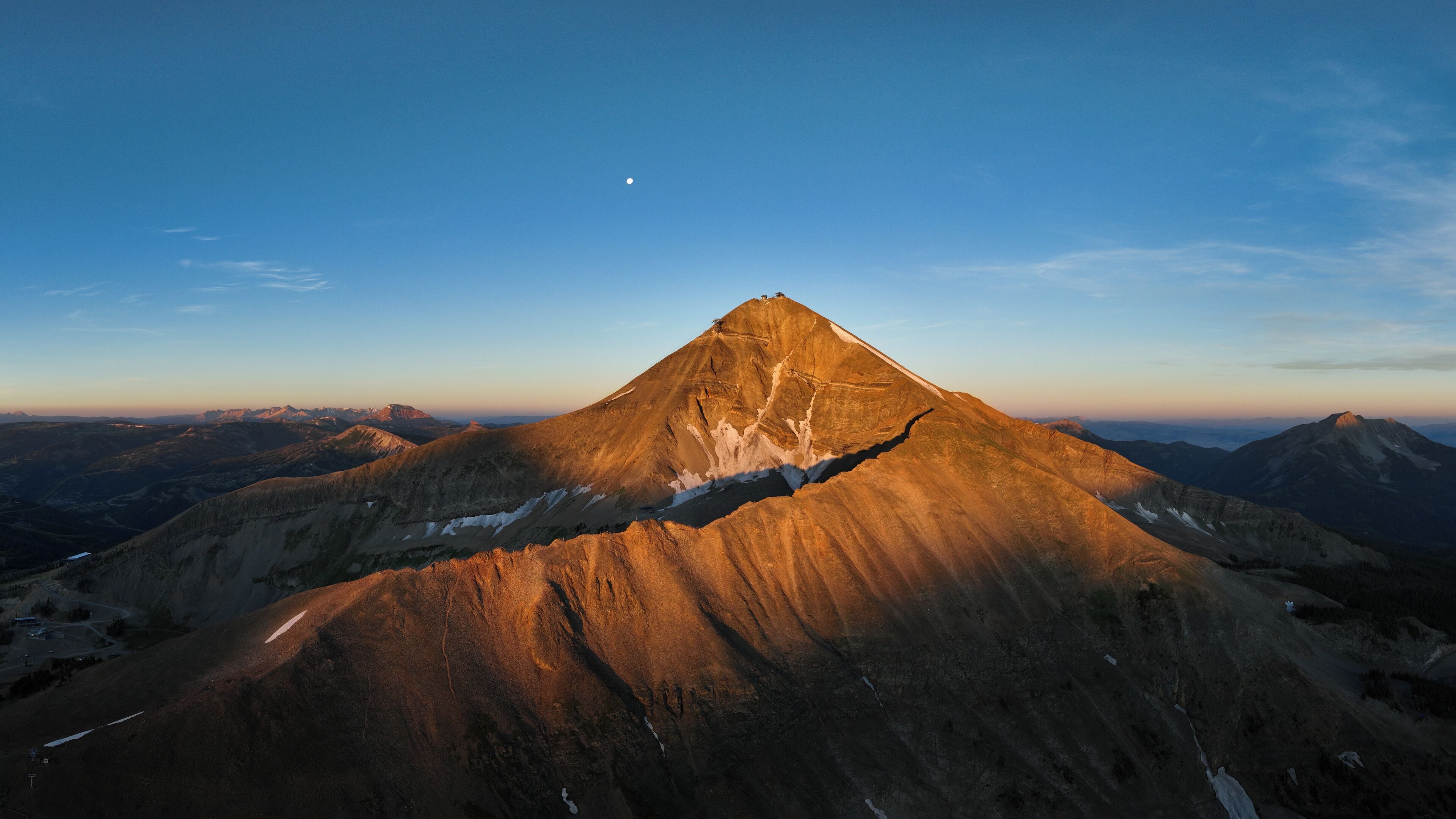 Een berg met een duidelijke top, omringd door andere bergen en een heldere lucht.