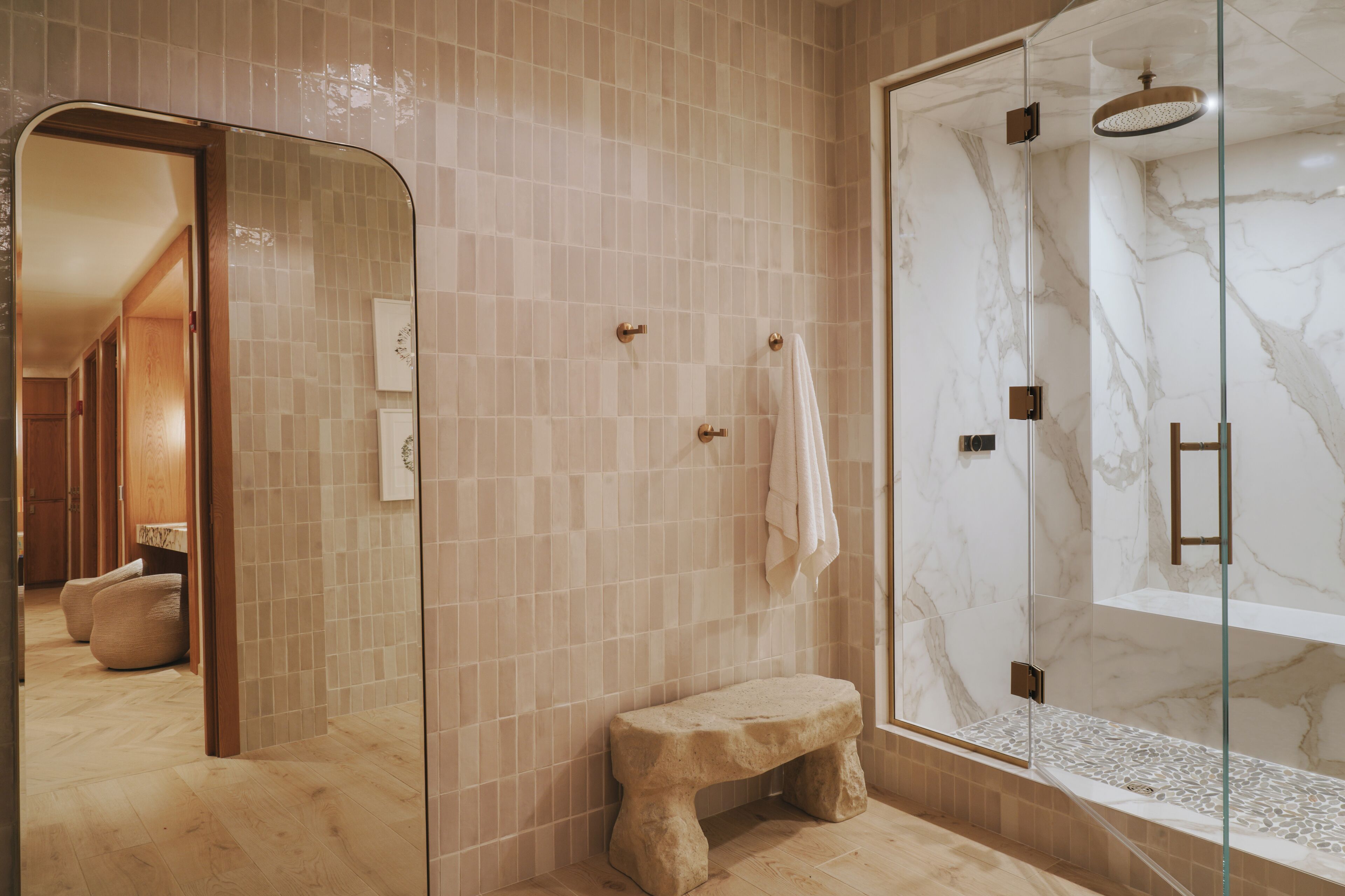 Une salle de bain moderne avec une douche à parois de verre, un banc en pierre et un mur recouvert de carreaux.
