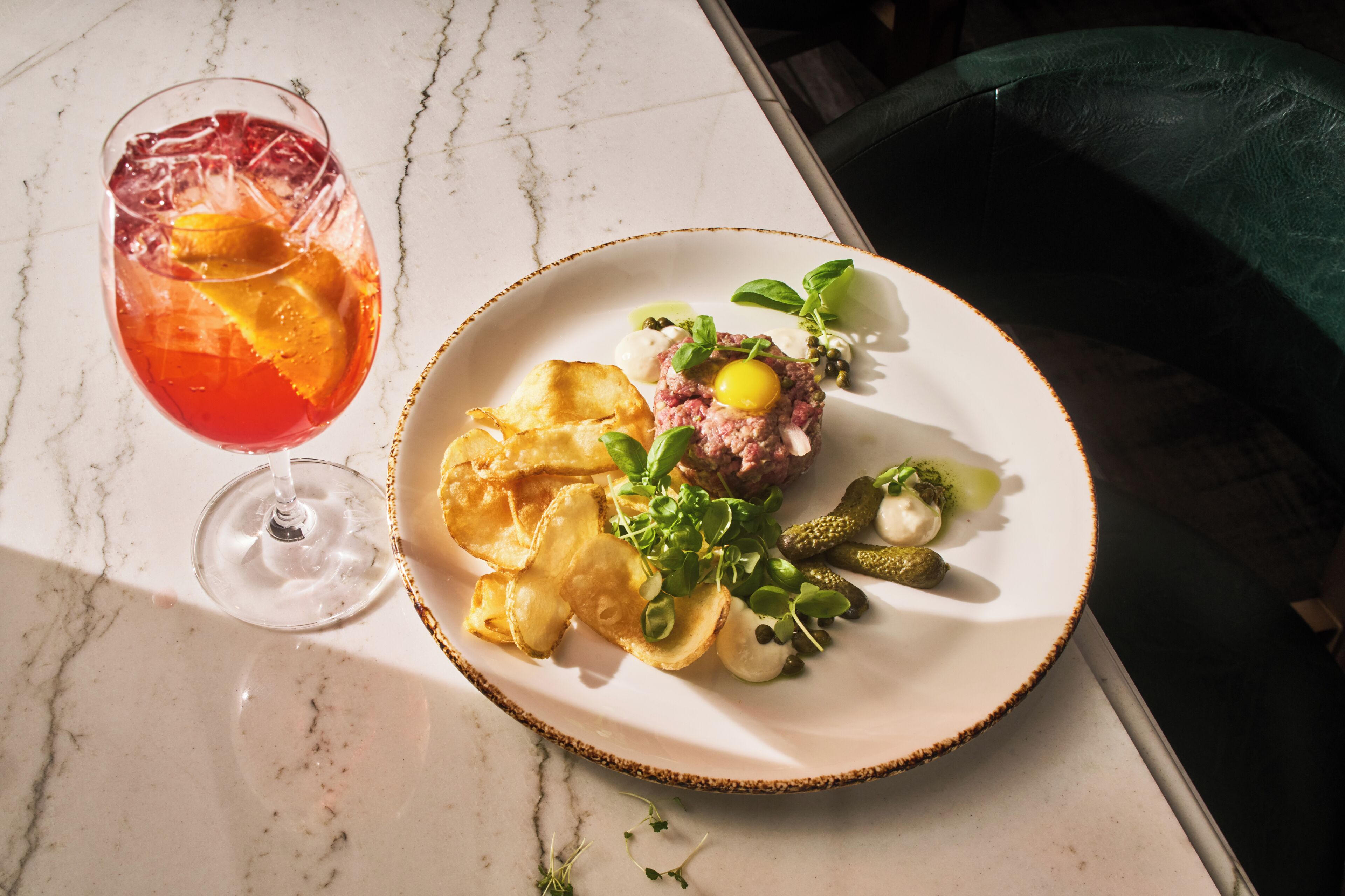 A plate of food with a drink on a marble table.