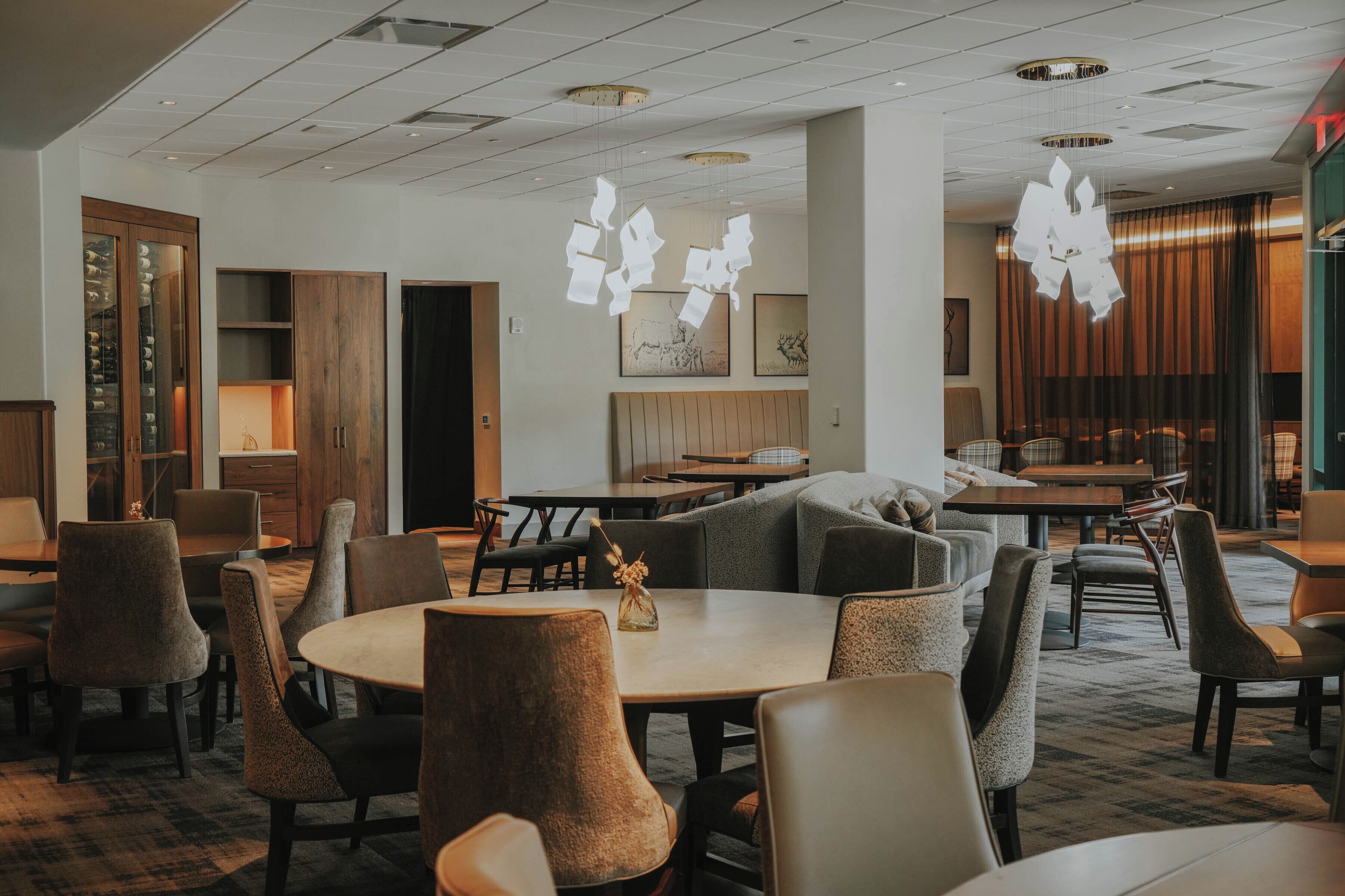 Een hotel lobby met ronde tafels, zachte zitplaatsen, houten kasten en hangende papieren decoraties.