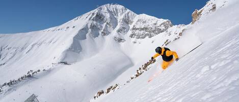 A snowy mountain slope with a skier in motion.